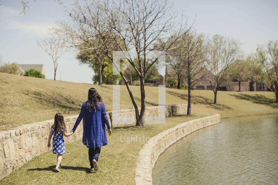 mother and daughter walking holding hands in a park