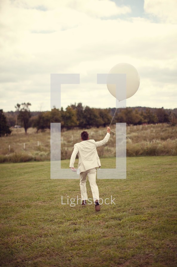 man in a suit running holding a white balloon