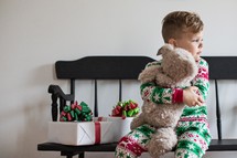 toddler boy hugging a teddy bear at Christmas 