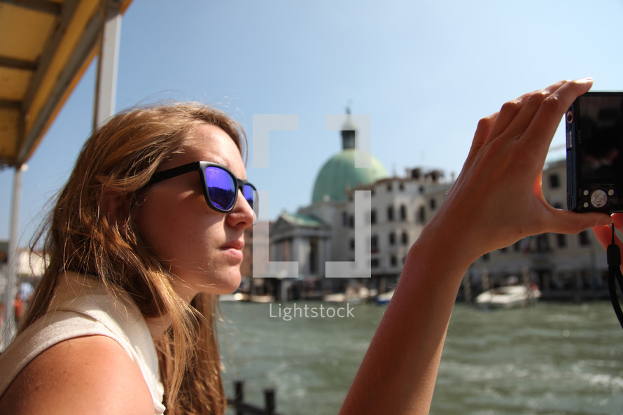 woman taking a picture with a camera from a boat in Venice 