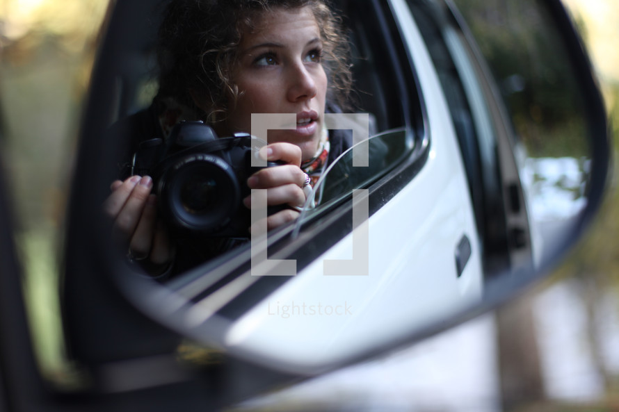 woman sitting in her car holding a camera 