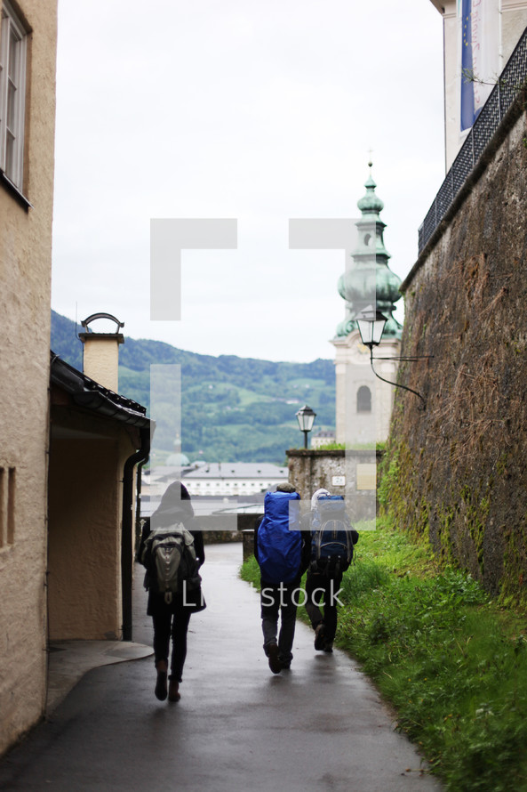 men with backpacks walking along a side street 
