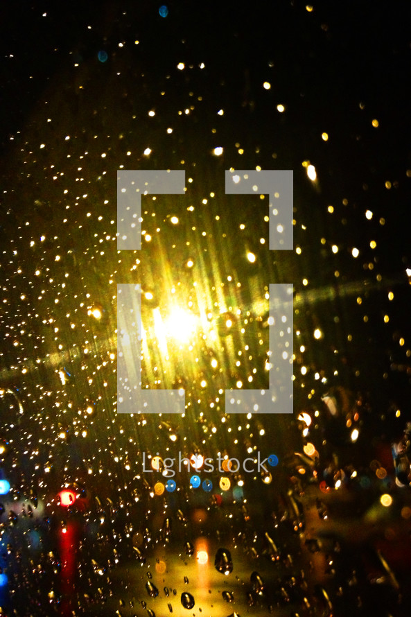Lights shining through raindrops on a window.