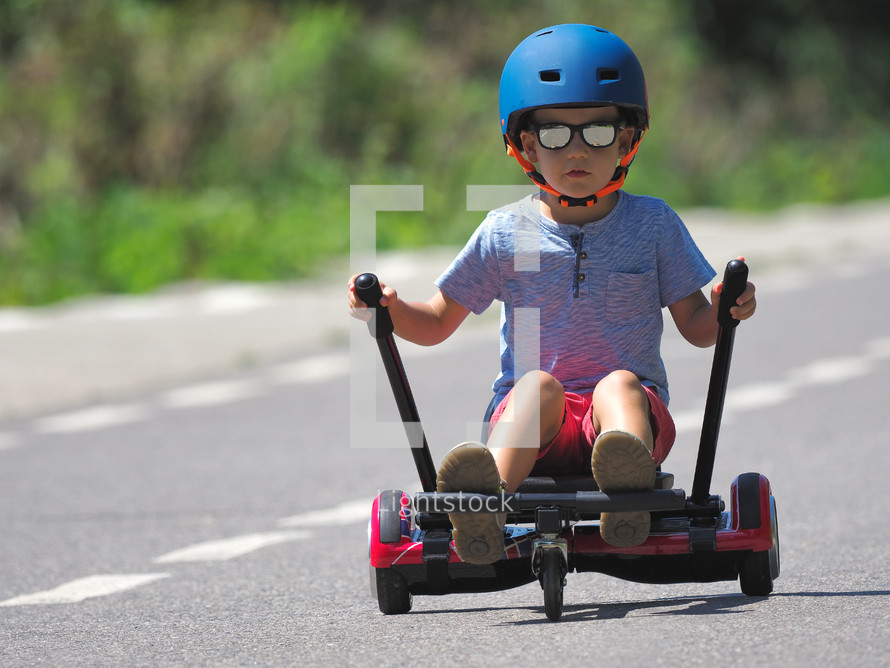 boy on hoverboard or gyroscooter with kart accessory kit outdoor. New modern technologies