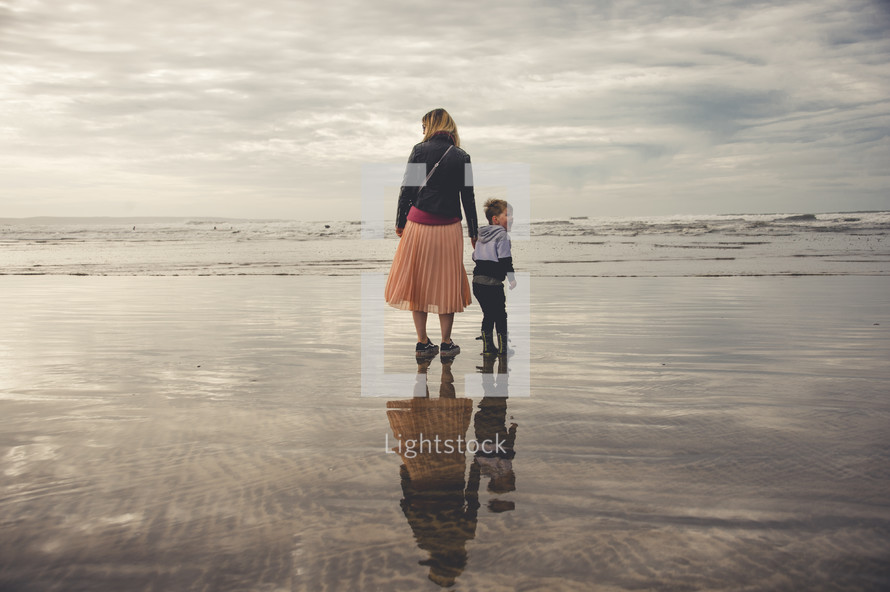 a mother and son walking on a beach 