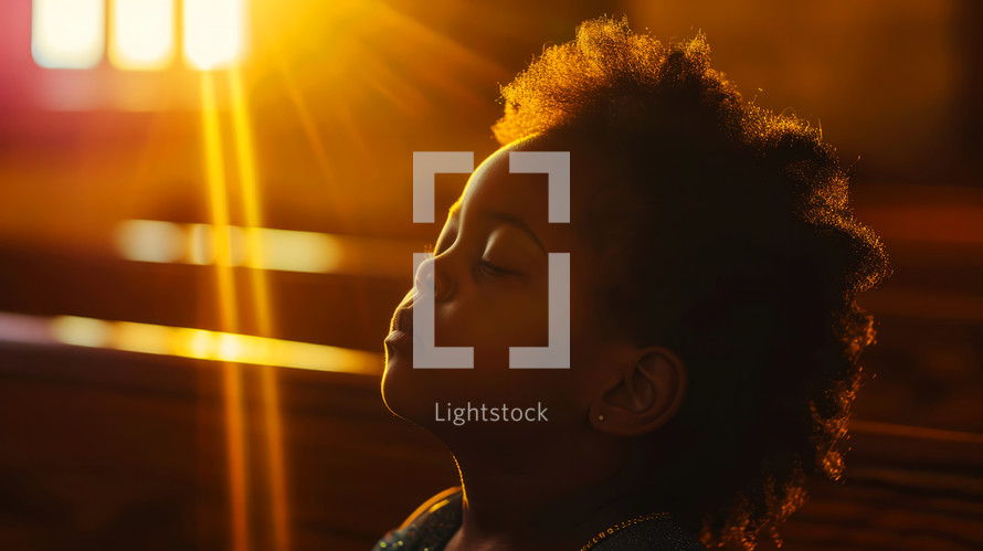 Portrait of beautiful african american girl with closed eyes in the sunlight, praying.