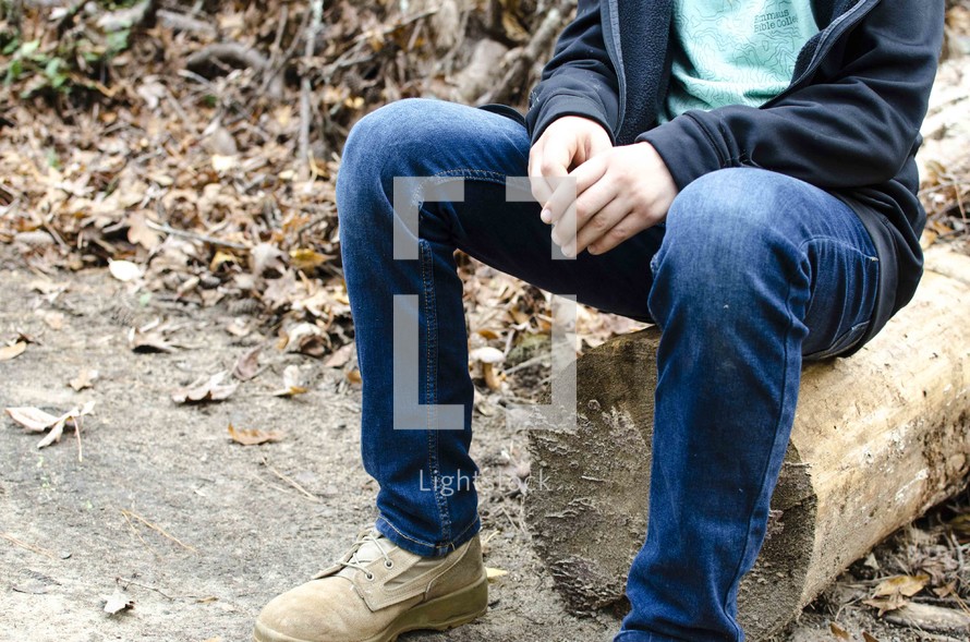 legs of a boy sitting on a log 