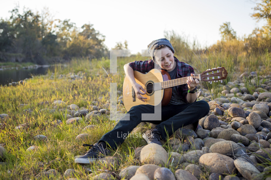 boy playing a guitar outdoors 