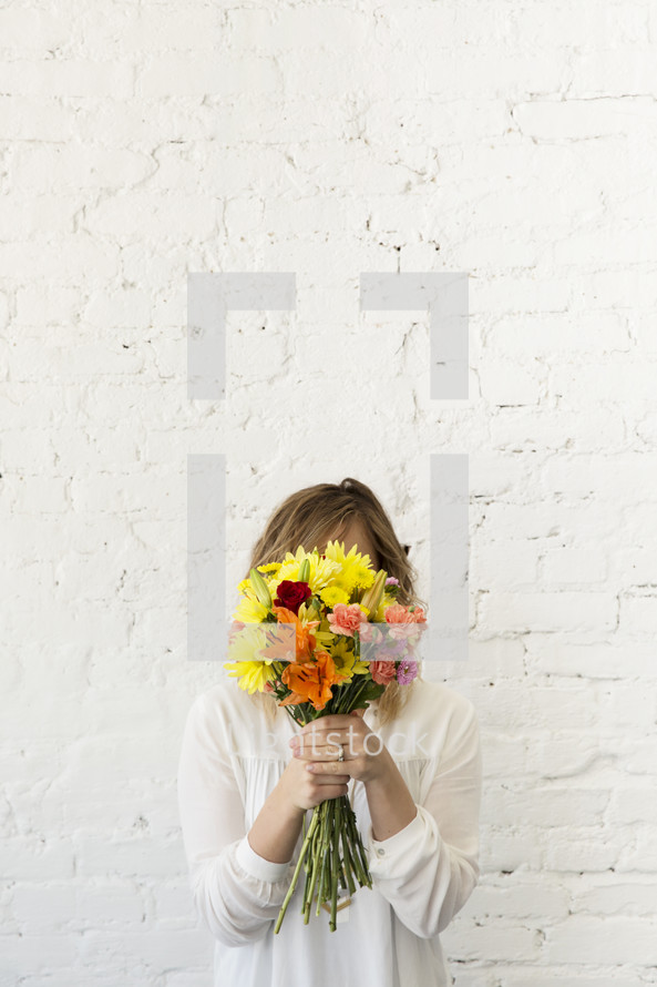a woman hiding behind a bouquet of flowers 