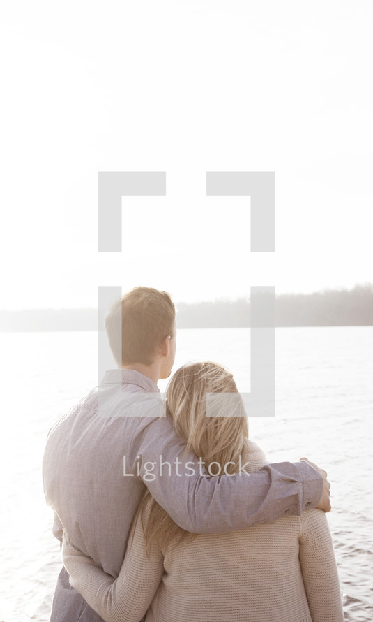 couple standing together in front of a lake 