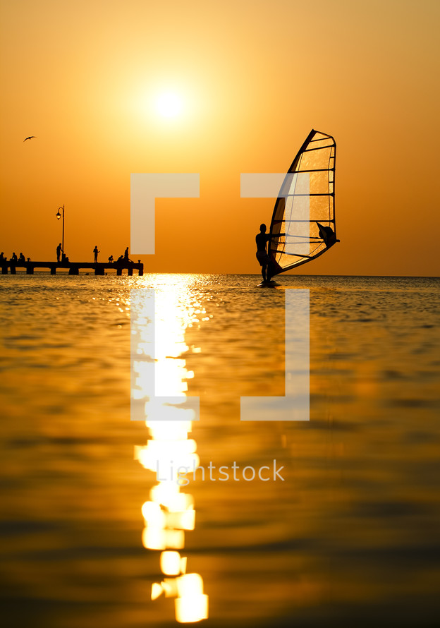 Silhouette of surfer at sunset passing by