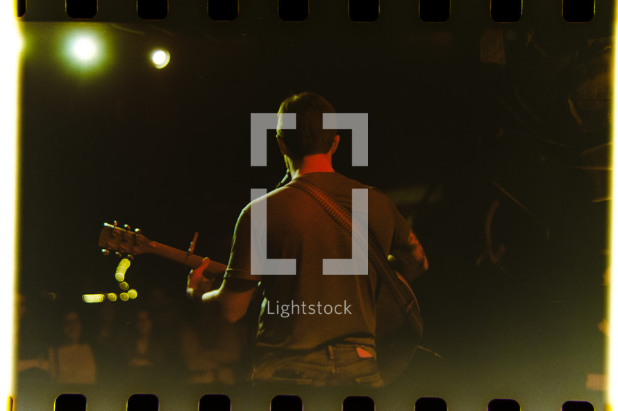 a man on stage playing a guitar on a filmstrip 