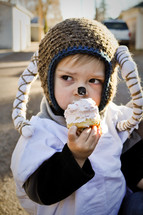 boy child dressed as a ram eating a cupcake 