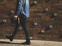 A man walking on sidewalk carrying a Bible 