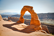 Two hikers stand under the Delicate Arch in Moab, Utah.