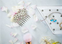 jewel studded hair comb, makeup brush, and flower petals 