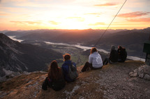 people sitting at the top of a mountain at sunrise 