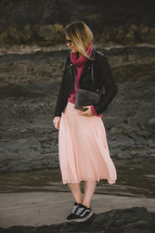 a woman walking on a rocky beach 