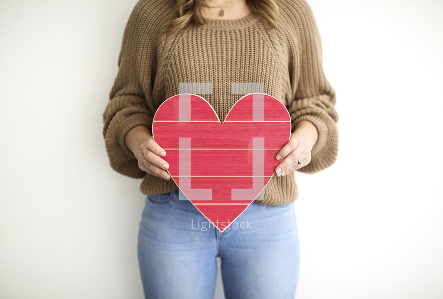 a woman holding a red wooden Valentine's Day heart 