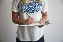 a woman filling out a document on a clipboard 