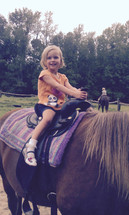 a little girl riding a pony 