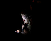 a man looking at his cellphone in darkness 