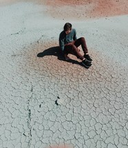 man sitting on parched soil 