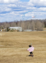Child flying a kits in an open field.
