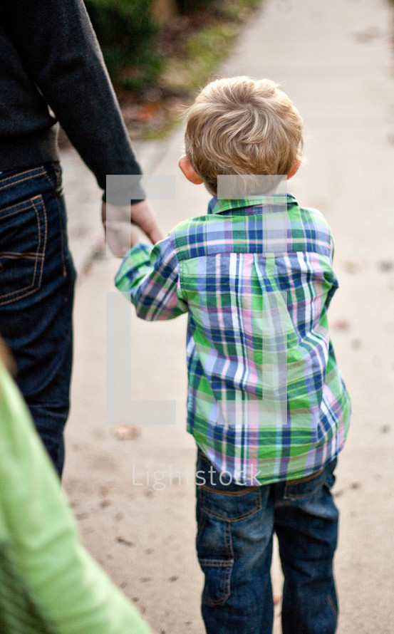 toddler boy walking holding his fathers hand