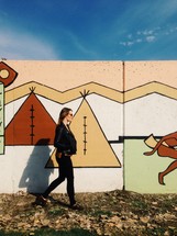 woman walking in front of a Tee Pee painting 