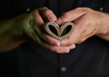 Person holding money shaped like a heart with two hands