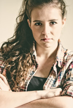 A teenage girl with arms crossed and an angry countenance.