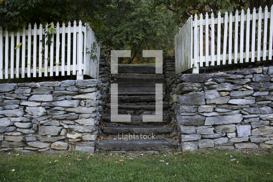 white picket fence at the top of a stone wall 