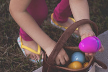 a child putting an Easter egg in a basket 
