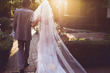 A bride and groom walking into the sun