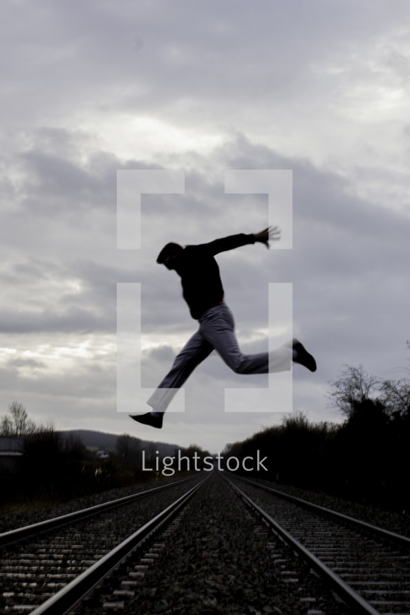 a man jumping over railroad tracks 