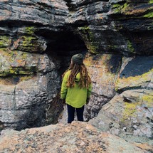 A woman standing in front of a narrow cave