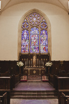A church altar with a stained glass window in the background