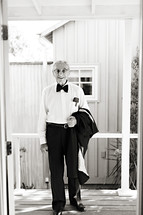 Elderly man in suit  smiling holding jacket in hand on porch tuxedo 