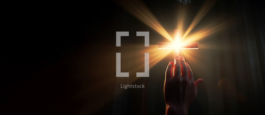 Hand reaching for the cross with light rays on a dark background. Copy space