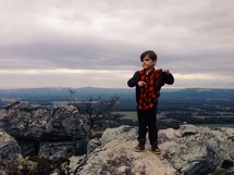 little boy standing at the top of a mountain 