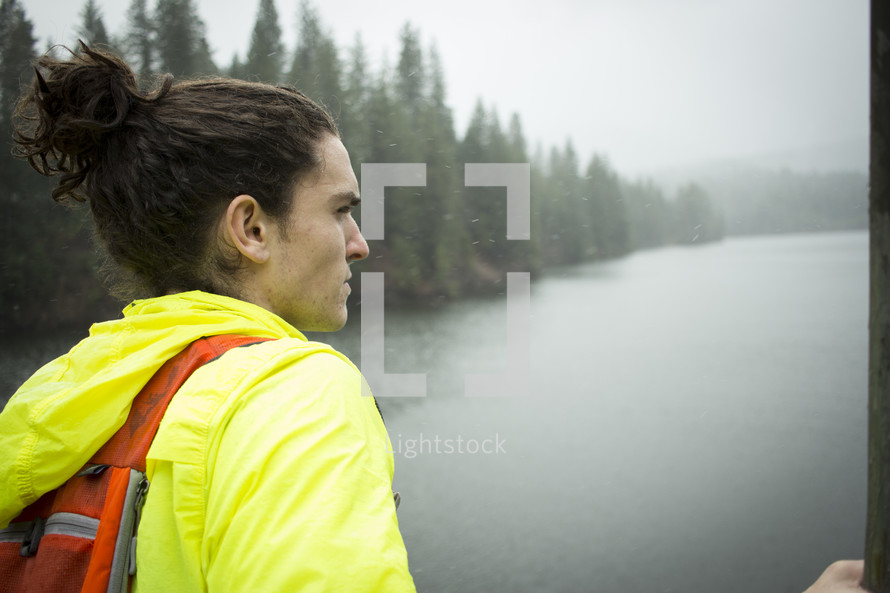 a man standing by a lake in falling rain 