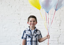a boy child holding balloons 