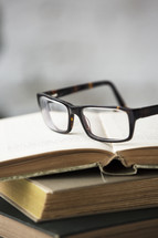 reading glasses on a stack of old books 