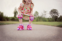 child in roller skates and knee pads 