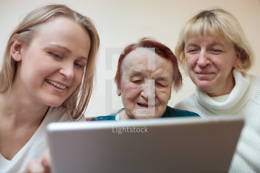 Three women using a smart tablet