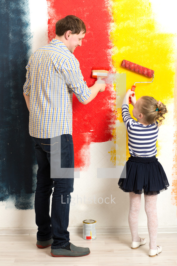 Father and daughter painting wall
