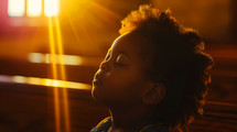 Portrait of beautiful african american girl with closed eyes in the sunlight, praying.