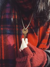 woman holding a key on a chain around her neck 