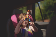 a child in a carseat holding a toy 